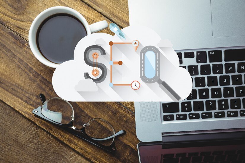 Lettres SEO et loupe dans un nuage, posés sur un bureau à côté d'un ordinateur portable et d'une tasse de café